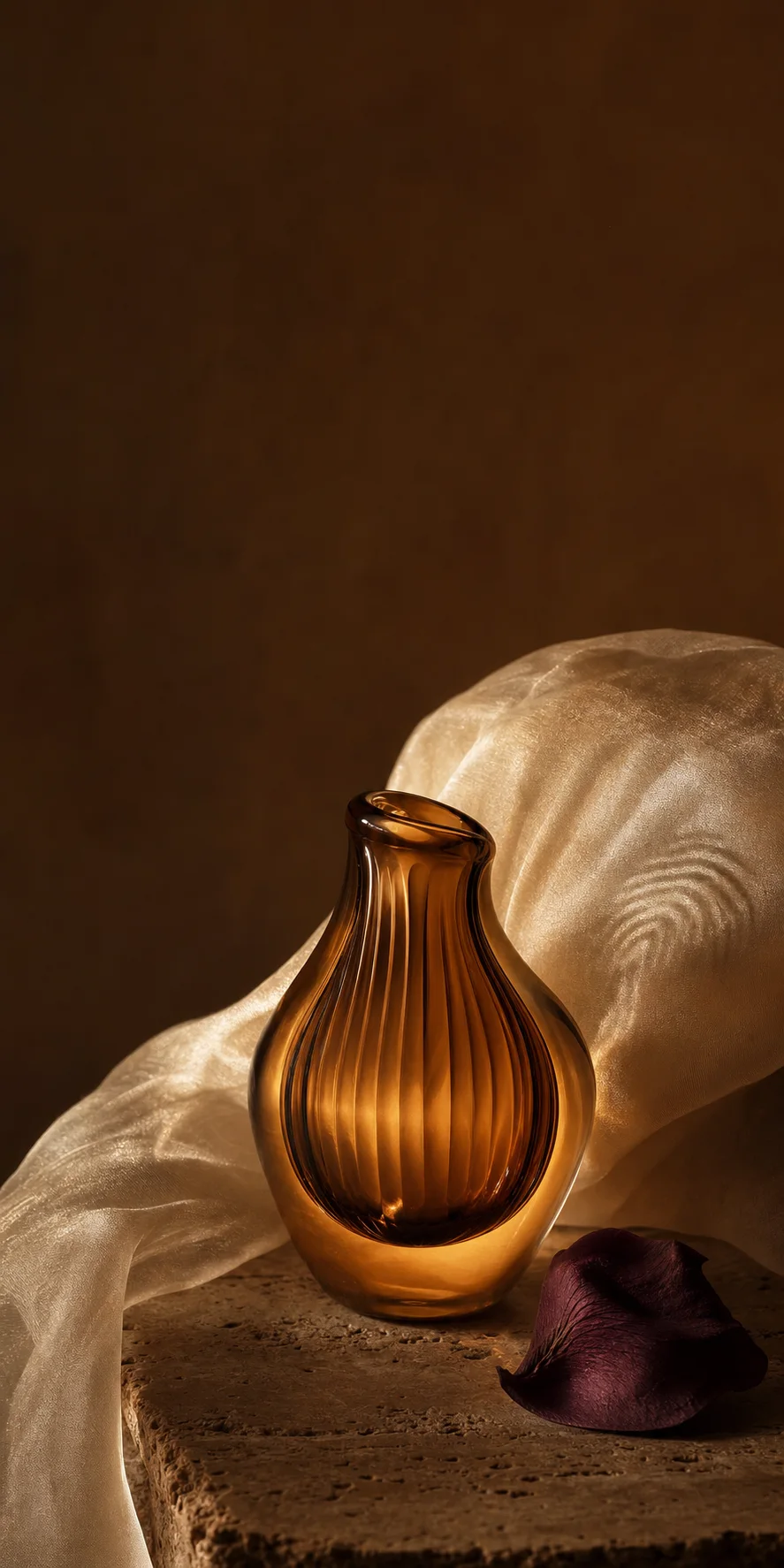An amber vessel resting in ivory silk with warm, fingerprint-like light